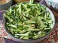 Una ciotola piena di fresca insalata di cetrioli tagliati a julienne, condita con semi di sesamo e arachidi croccanti.