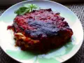Una porzione di parmigiana di melanzane napoletana, ricca e saporita, guarnita con basilico fresco.