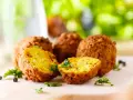 Polpette di ceci dorate e croccanti, cotte in friggitrice ad aria, guarnite con prezzemolo fresco su tagliere di legno.