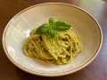 Spaghetti conditi con un cremoso pesto di limone, guarniti con basilico fresco. Una deliziosa ricetta per un primo piatto estivo.