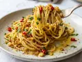 Spaghetti con acciughe e pangrattato, un piatto semplice ma gustoso, con un tocco di peperoncino e prezzemolo fresco.
