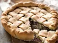 Pizza di scarola con un intreccio dorato di pasta e un ripieno invitante di verdure e olive.