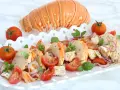 Aragosta alla catalana, un piatto fresco con aragosta, pomodorini, cipolla rossa e basilico, servito su un vassoio bianco.