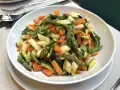Un piatto invitante di verdure in padella: asparagi, carote e zucchine tagliate a pezzetti, condite con un filo d'olio.