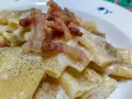 Un piatto di pasta alla gricia fumante, con guanciale croccante e abbondante pepe nero.
