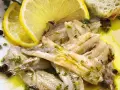 Alici in padella, succulente e dorate, condite con limone fresco, prezzemolo e pepe nero. Un piatto semplice e gustoso.