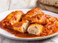 Calamari ripieni in padella, soffocati in un sugo rosso saporito, con un ripieno visibile e prelibato.