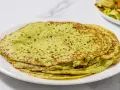 Piatto di crepes di zucchine verdi, sottili e leggermente dorate, impilate su un piatto bianco.