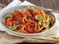 Pasta con sugo rosso, olive, acciughe e basilico, un assaggio di **stroncatura calabrese**.