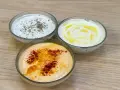 Tre ciotole di salsa con yogurt greco: una con erbe, una con olio d'oliva e una con paprika.