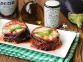Deliziosa parmigiana di melanzane grigliate, con strati di melanzane, sugo e formaggio filante, guarnita con basilico fresco.