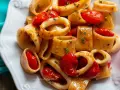 Un invitante sugo di pesce con anelli di calamaro e pomodorini, guarnito con prezzemolo fresco.