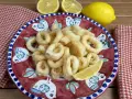 Un piatto di **calamari fritti** dorati, guarnito con spicchi di limone fresco, su un piatto decorato con uccelli stilizzati.