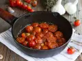 Pomodorini confit in padella, dolci e succosi, cotti con aglio e erbe aromatiche. Un contorno saporito e profumato.
