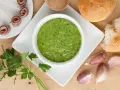 Un invitante bagnetto verde piemontese, accompagnato da acciughe arrotolate, pane fresco e spicchi d'aglio.