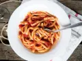 Piatto di pasta fresca condita con un saporito sugo all'aglione, servito su un piatto bianco con una forchetta.