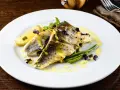 Deliziosi secondi di pesce con fagiolini croccanti, limone e una salsa gialla cremosa, guarniti con erbe viola.