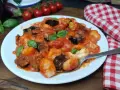 Gnocchi all'ortolana con melanzane, pomodorini e basilico fresco, un piatto colorato e saporito.