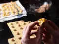 Mani che creano tortellini fatti in casa, con la pasta fresca e il ripieno pronto.