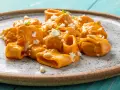 Paccheri cremosi con salsa arancione, formaggio sbriciolato e pinoli. Un piatto che ricorda il sapore del brodo vegetale Bimby.
