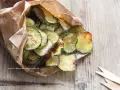 Delizioso contorno di zucchine fritte, croccanti e dorate, servite in un sacchetto di carta.