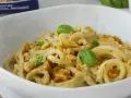 Pasta condita con un cremoso pesto di noci, guarnita con basilico fresco e noci croccanti.