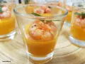 Deliziosi finger food gamberi su crema arancione in bicchierini, guarniti con menta.