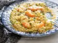 Un cremoso risotto zucchine e gamberetti, servito su un piatto decorato.