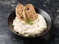 Mousse di tonno cremosa con erbe aromatiche, guarnita con aneto e servita con fette di pane integrale tostato.