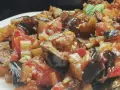 Un primo piano di una saporita caponata siciliana, con melanzane, pomodori e sedano cotti a puntino.