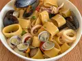 Calamarata allo scoglio ricca di cozze, vongole e anelli di calamaro, un piatto di mare invitante.