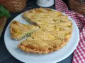 Una deliziosa crostata salata con zucchine e formaggio, con una griglia di pasta dorata e un pezzo tagliato.