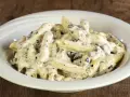 Penne cremose con pezzetti scuri, un piatto invitante di pasta alla cenere, servito in una ciotola bianca su un tavolo di legno rustico.