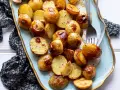 Patate novelle al forno dorate e croccanti, servite su un piatto azzurro con forchetta.