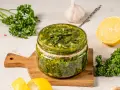 Un vasetto di salmoriglio ricetta, con prezzemolo fresco, limone e aglio, pronto per insaporire i tuoi piatti.