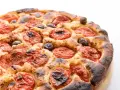 Focaccia barese dorata e fragrante, con pomodorini succosi e olive nere, pronta per essere gustata.