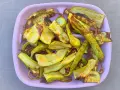 Piatto rosa pieno di zucchine grigliate, tagliate a listarelle e leggermente abbrustolite, pronte per essere gustate.