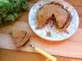 Torta salata con scarola, acciughe e mozzarella, appena sfornata, con una fetta servita su un piatto decorato.