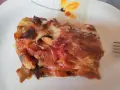Una fetta di lasagna di melanzane, ricca e saporita, con strati di melanzane, pomodoro e formaggio filante.