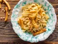 Piatto di ciceri e tria, pasta fresca con ceci e croccanti sfoglie fritte, servito in un piatto decorato.
