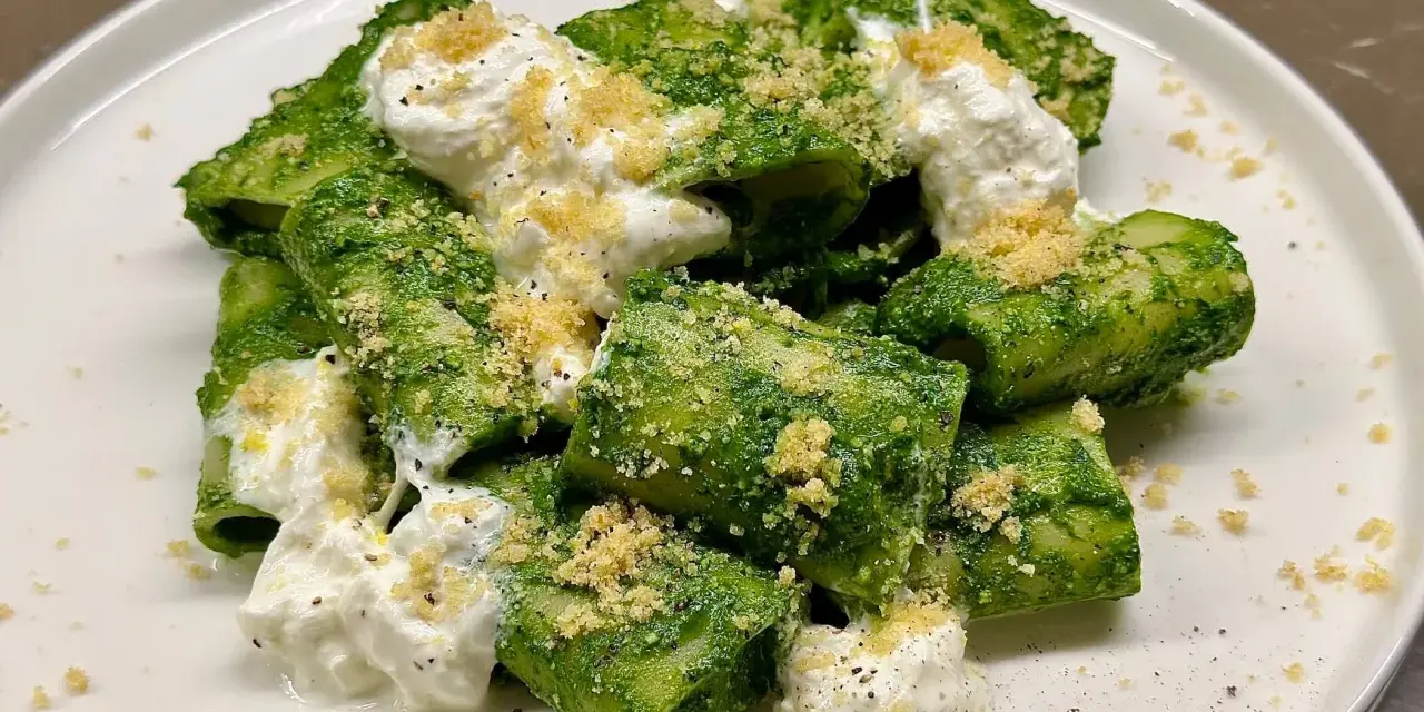 Paccheri conditi con un vibrante pesto di cavolo nero, arricchiti da ricotta cremosa e una spolverata di pangrattato croccante.