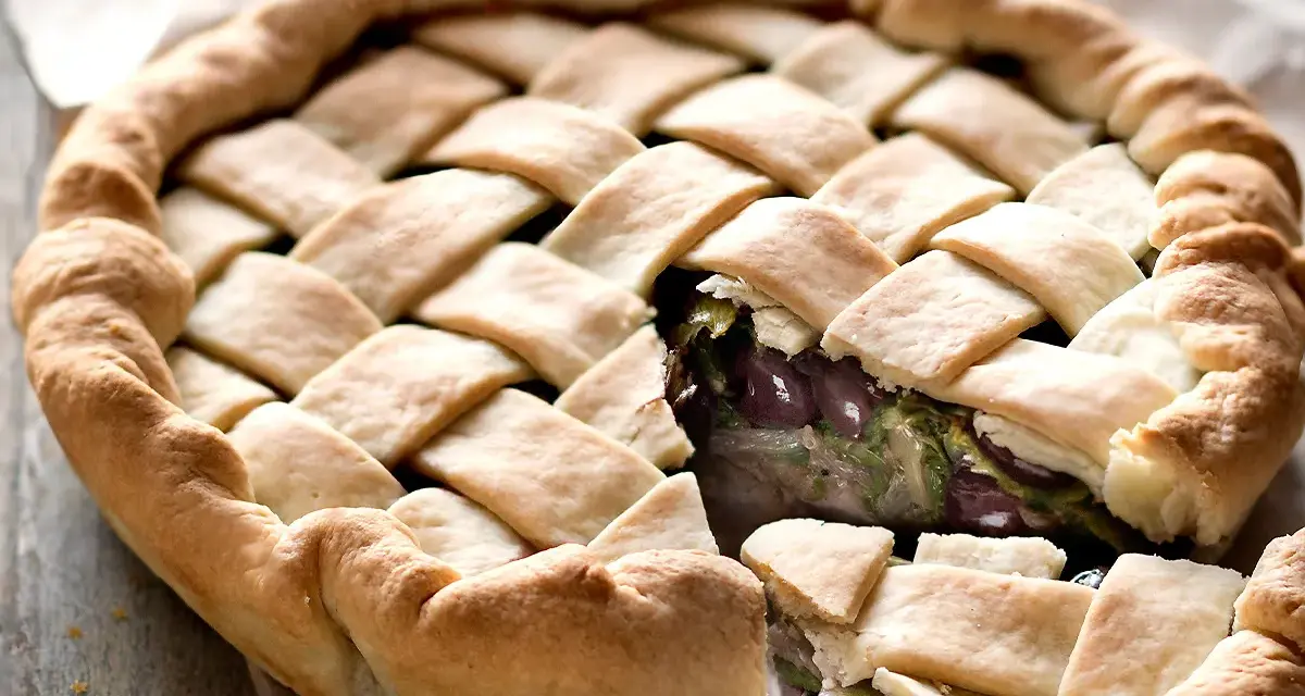 Pizza di scarola con un intreccio dorato di pasta e un ripieno invitante di verdure e olive.