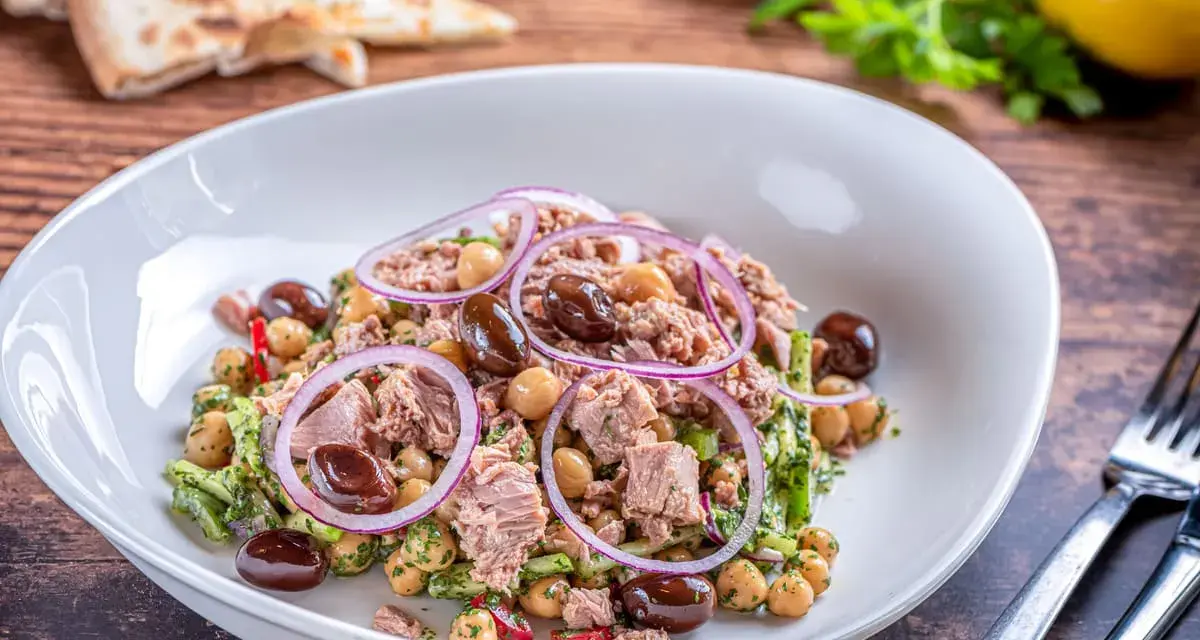 Deliziosa insalata di ceci e tonno con olive nere, cipolla rossa e prezzemolo fresco. Un piatto leggero e gustoso.
