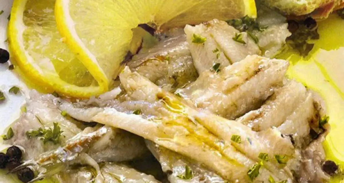 Alici in padella, succulente e dorate, condite con limone fresco, prezzemolo e pepe nero. Un piatto semplice e gustoso.