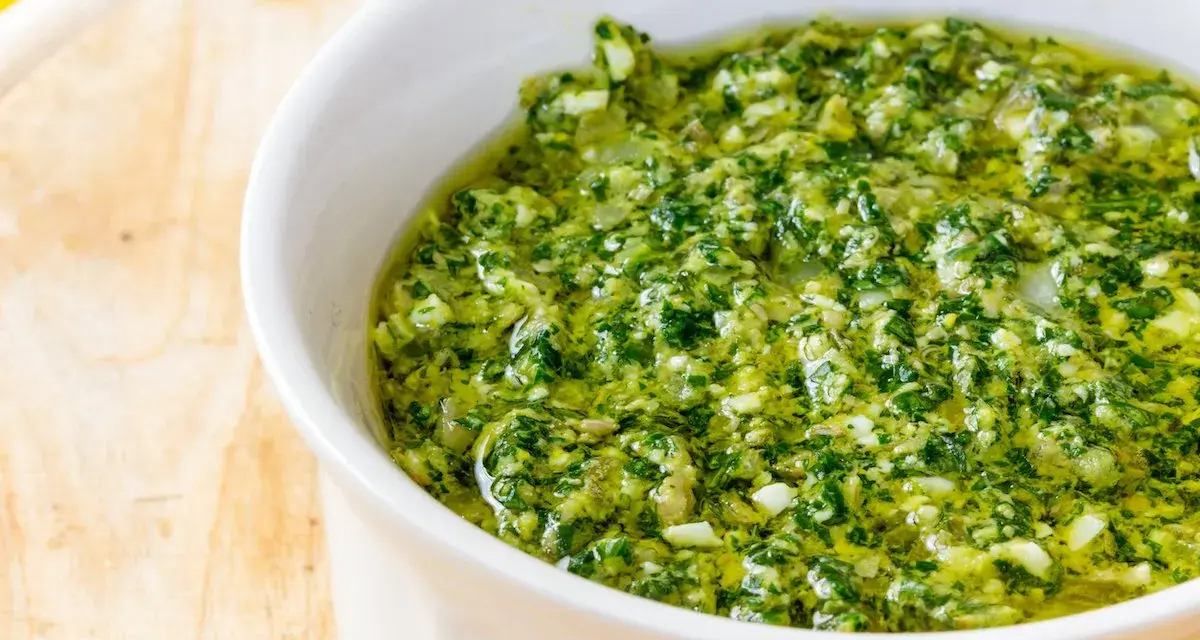 Una ciotola bianca piena di vibrante salsa verde, perfetta per accompagnare i tuoi piatti. Questa ricetta salsa verde è un'esplosione di freschezza.