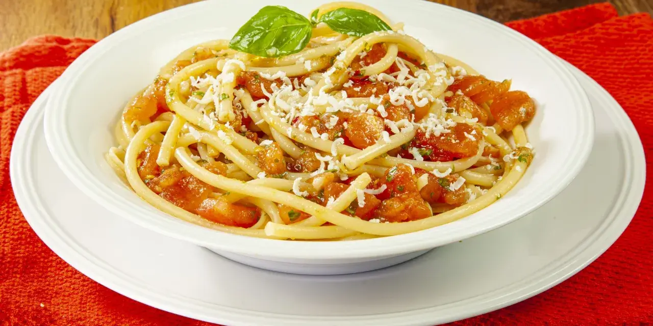 Un piatto invitante di pasta alla carrettiera, con pomodoro fresco, basilico e formaggio grattugiato.