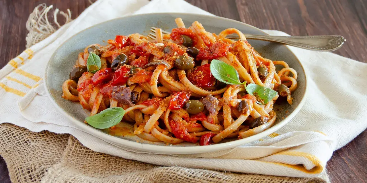 Pasta con sugo rosso, olive, acciughe e basilico, un assaggio di **stroncatura calabrese**.