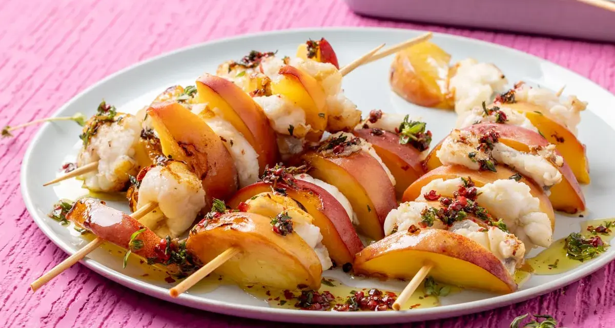 Spiedini per aperitivo veloci con pesche succose e bocconcini di pesce bianco, conditi con erbe aromatiche e olio.