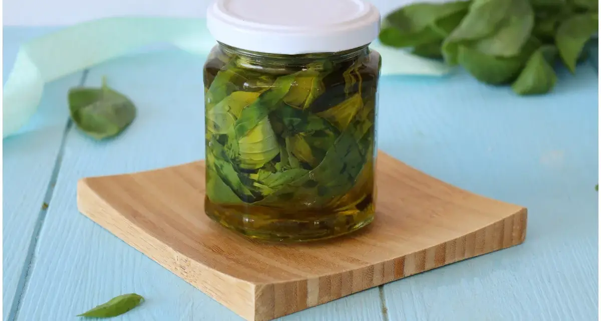 Un vasetto di basilico sott'olio, con foglie fresche sullo sfondo, pronto per insaporire i tuoi piatti.