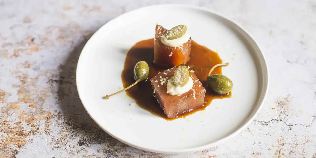 Cubetti di tonno vitellato con salsa bruna, capperi e una quenelle di maionese.